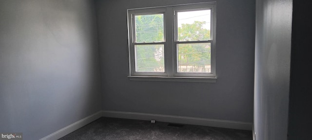unfurnished room with baseboards and dark carpet