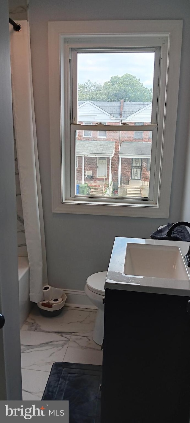bathroom featuring baseboards, marble finish floor, vanity, and a healthy amount of sunlight