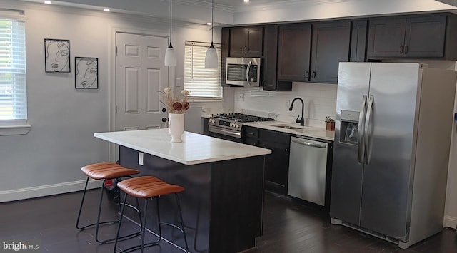 kitchen featuring a kitchen island, a breakfast bar area, light countertops, stainless steel appliances, and a sink