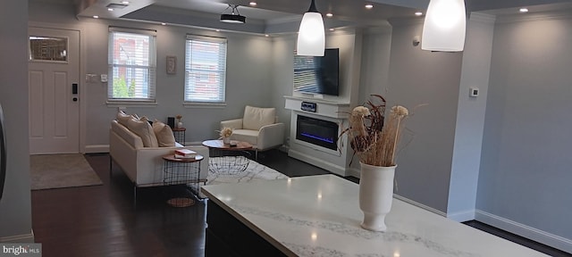 living room featuring a glass covered fireplace, dark wood-type flooring, baseboards, and ornamental molding