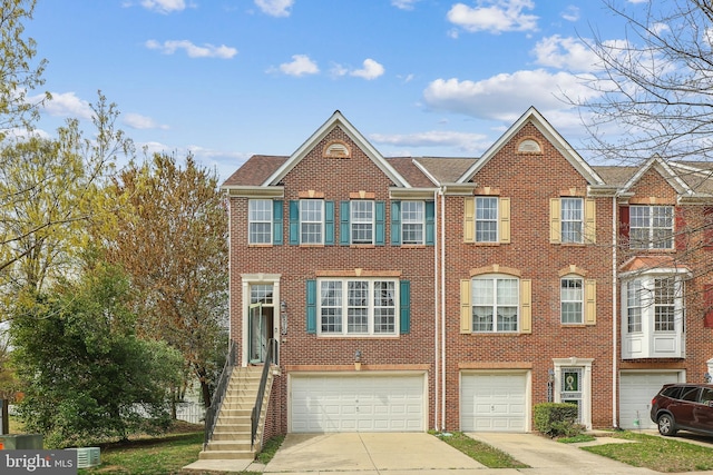 townhome / multi-family property featuring an attached garage, driveway, and brick siding