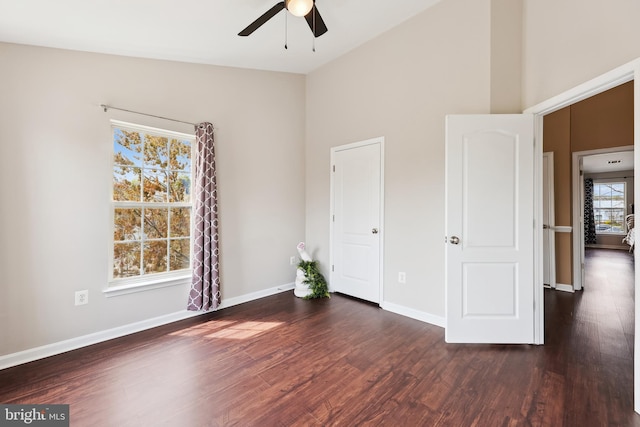 unfurnished bedroom featuring dark wood-type flooring, high vaulted ceiling, ceiling fan, and baseboards