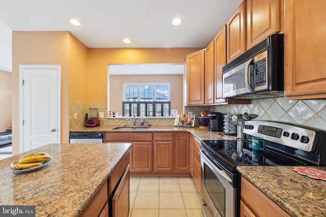 kitchen featuring light stone counters, a sink, backsplash, and stainless steel appliances