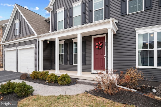 view of exterior entry with a porch and aphalt driveway