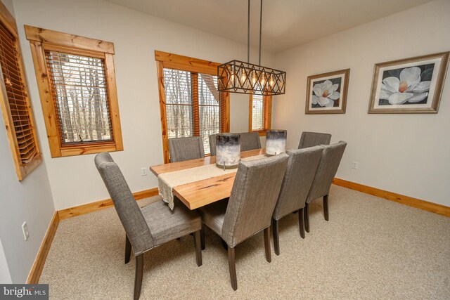 dining area with baseboards, light colored carpet, and an inviting chandelier