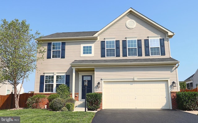 traditional home with brick siding, an attached garage, driveway, and fence