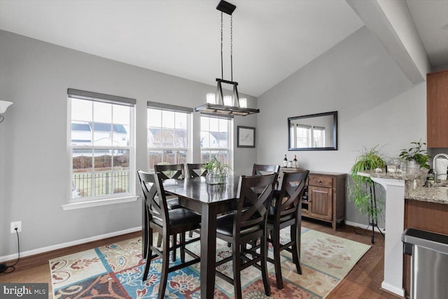 dining room with a healthy amount of sunlight, baseboards, lofted ceiling, and dark wood-style flooring