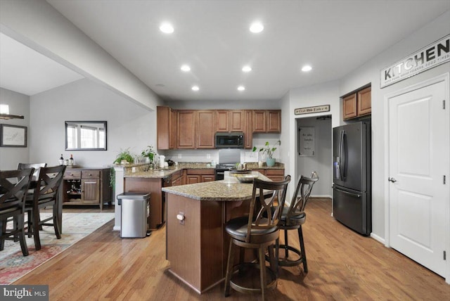 kitchen with stainless steel microwave, recessed lighting, light wood-style flooring, freestanding refrigerator, and stove