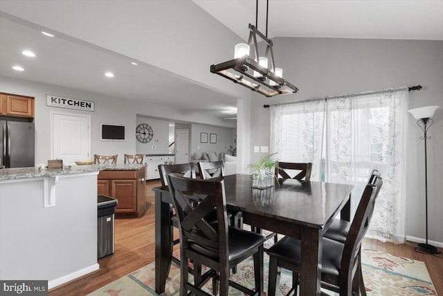 dining space with recessed lighting, light wood-type flooring, an inviting chandelier, and vaulted ceiling
