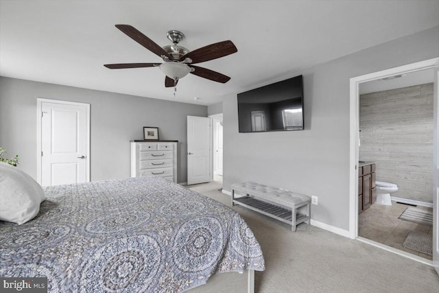 bedroom with a ceiling fan, light colored carpet, baseboards, and connected bathroom