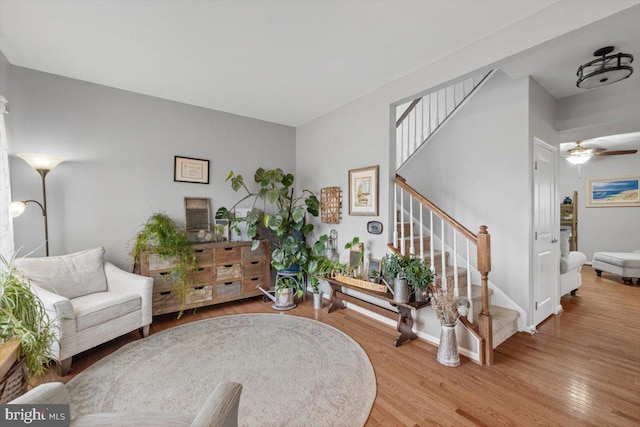 living area featuring ceiling fan, stairway, and wood finished floors