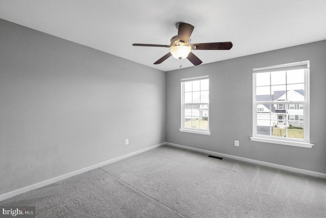 carpeted spare room with plenty of natural light, visible vents, and baseboards