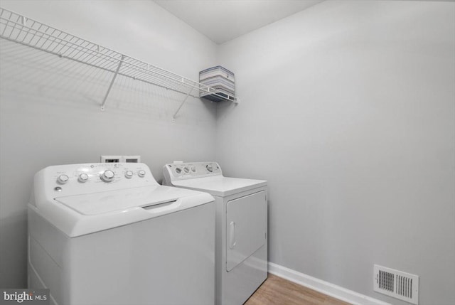 laundry area featuring visible vents, washer and dryer, light wood-style floors, baseboards, and laundry area