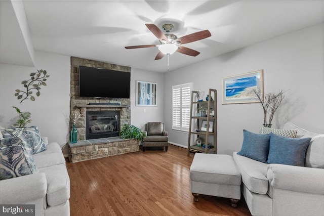 living room featuring a fireplace, wood finished floors, and a ceiling fan