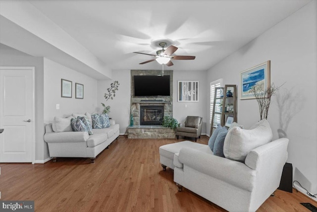 living area featuring visible vents, a ceiling fan, wood finished floors, and a fireplace