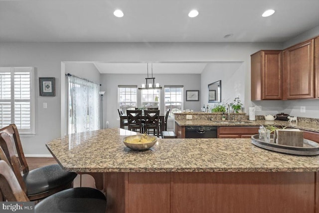 kitchen with a sink, recessed lighting, a peninsula, brown cabinetry, and dishwasher