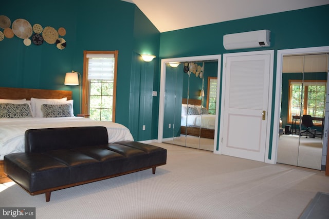carpeted bedroom with vaulted ceiling, two closets, and a wall mounted air conditioner