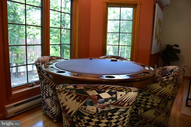 dining room featuring a wall mounted AC, a baseboard heating unit, and hardwood / wood-style flooring