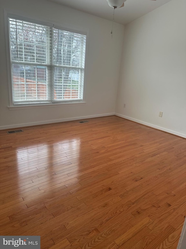 unfurnished room featuring visible vents, baseboards, and wood finished floors