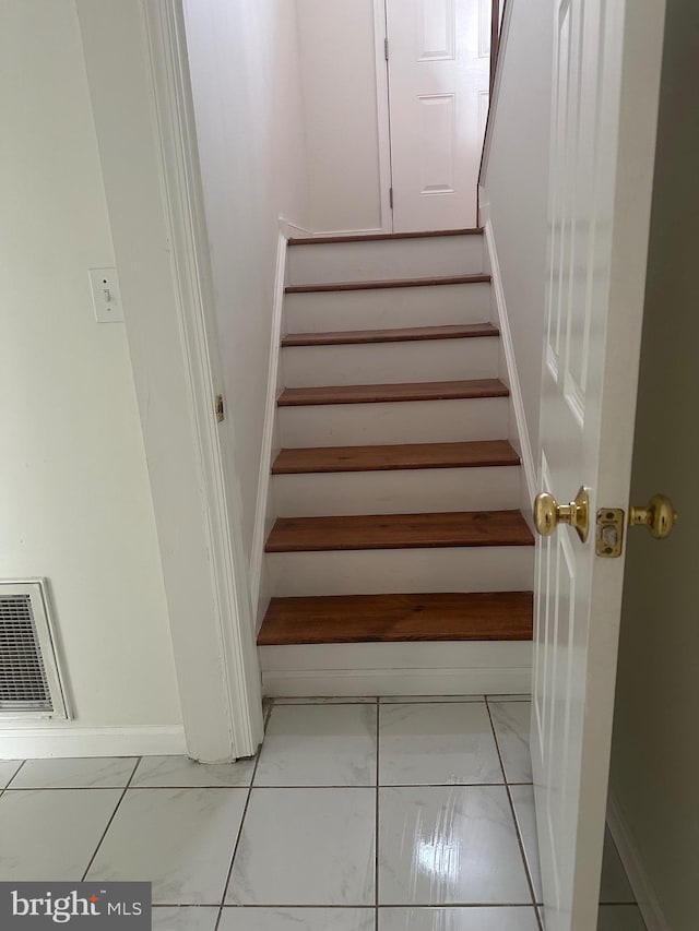 stairway featuring visible vents, marble finish floor, and baseboards