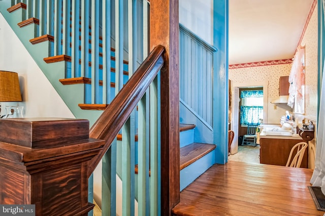 stairway featuring wallpapered walls and wood finished floors