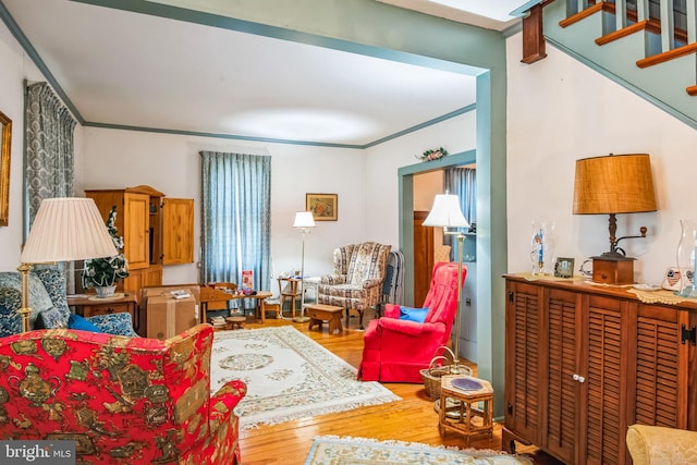 living area featuring stairs, crown molding, and wood finished floors