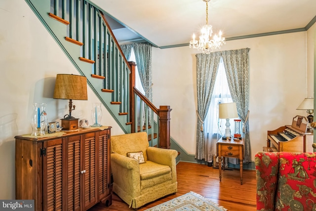 sitting room featuring stairway, crown molding, an inviting chandelier, and wood finished floors
