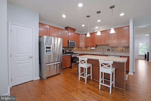kitchen with wood-type flooring, decorative backsplash, a kitchen island, and stainless steel appliances