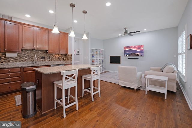 kitchen with tasteful backsplash, dark wood-style flooring, a sink, open floor plan, and a breakfast bar area