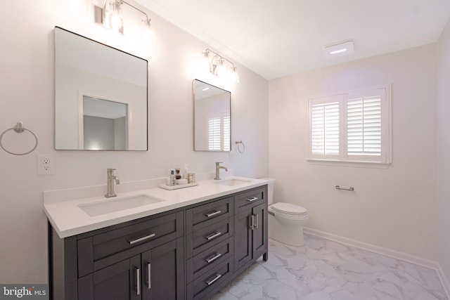 full bath with toilet, double vanity, marble finish floor, and a sink