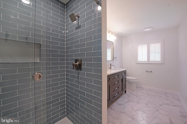 bathroom featuring vanity, baseboards, toilet, tiled shower, and marble finish floor