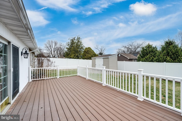 deck with a fenced backyard, an outdoor structure, and a shed