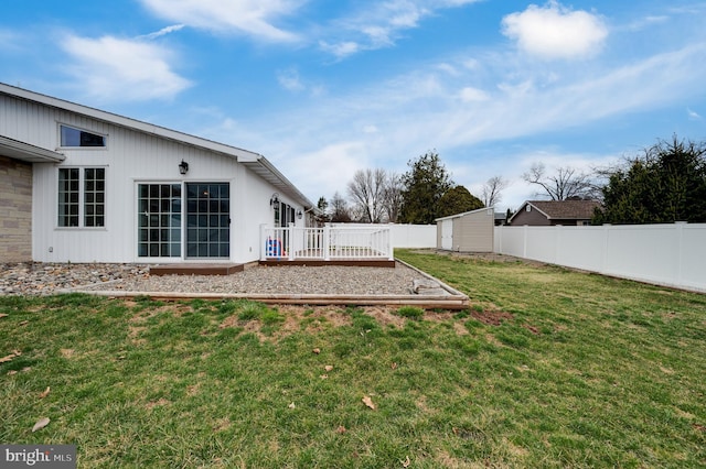 view of yard featuring a storage unit, a wooden deck, an outbuilding, and a fenced backyard