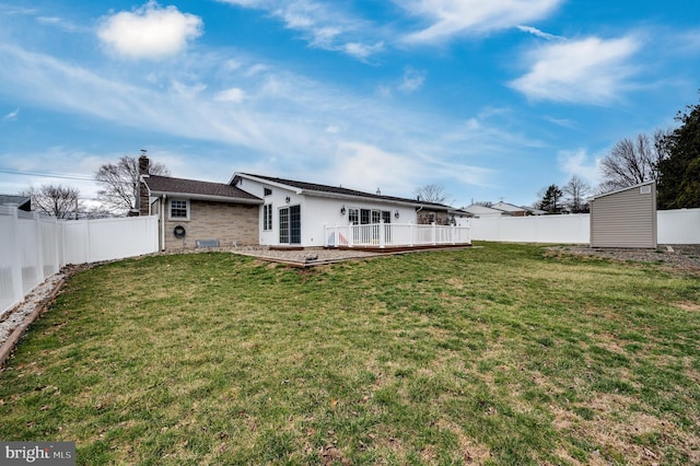 back of property with a yard, a wooden deck, and a fenced backyard