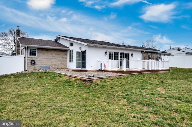 rear view of house featuring a lawn, a deck, a chimney, and fence