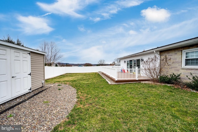 view of yard featuring an outbuilding, a storage unit, a fenced backyard, and a wooden deck