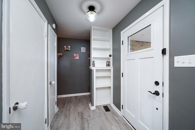 doorway featuring visible vents, baseboards, and light wood finished floors