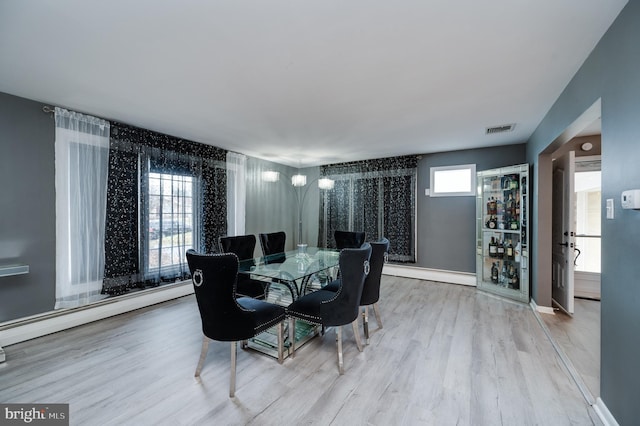 dining space featuring visible vents, wood finished floors, and a baseboard heating unit