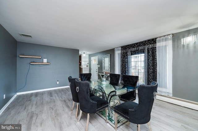 dining space with a baseboard radiator, wood finished floors, visible vents, and baseboards
