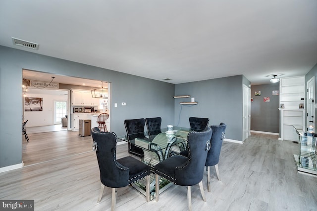 dining area with visible vents, light wood-type flooring, and baseboards