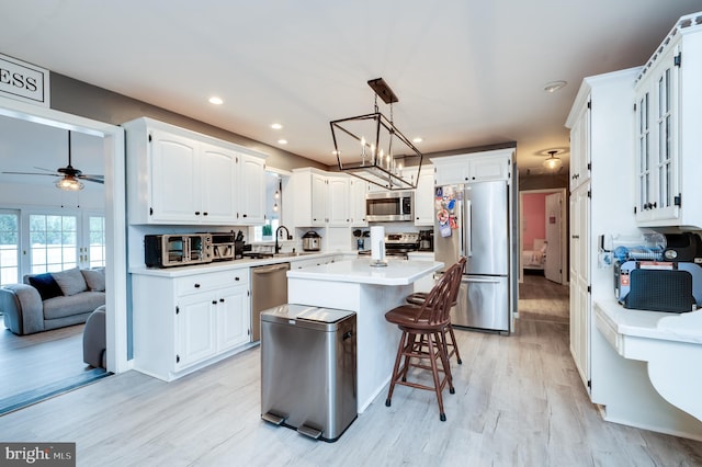 kitchen with appliances with stainless steel finishes, white cabinetry, light countertops, and a sink