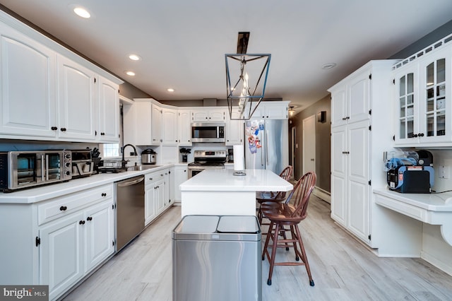 kitchen with a sink, light wood finished floors, white cabinetry, and stainless steel appliances