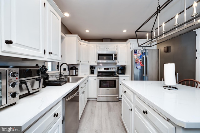 kitchen featuring a sink, an inviting chandelier, white cabinetry, and stainless steel appliances