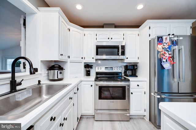 kitchen with light countertops, white cabinets, appliances with stainless steel finishes, and a sink