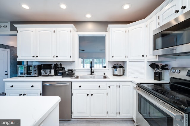 kitchen featuring light countertops, recessed lighting, white cabinets, stainless steel appliances, and a sink