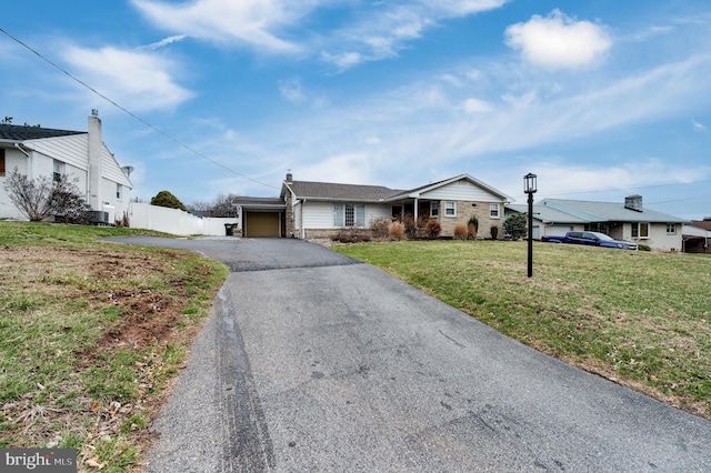 ranch-style house with a garage, a front lawn, driveway, and fence