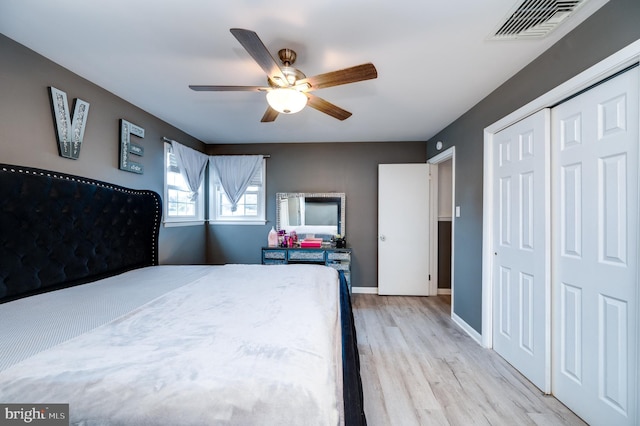 bedroom featuring visible vents, baseboards, wood finished floors, a closet, and a ceiling fan