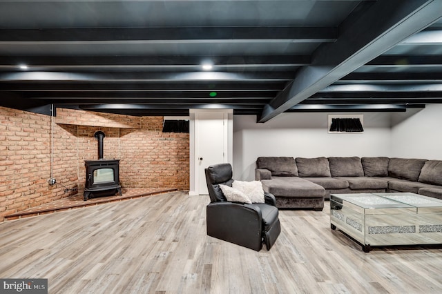 living room with beamed ceiling, brick wall, a wood stove, and wood finished floors