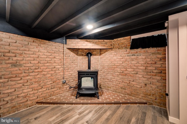 details featuring a wood stove, wood finished floors, and beamed ceiling