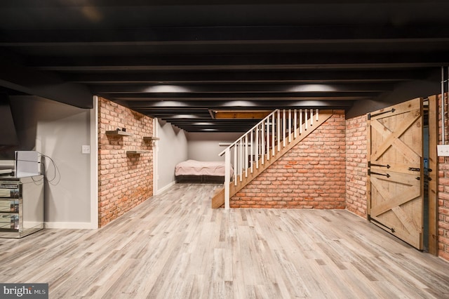 finished basement with wood finished floors, baseboards, and brick wall